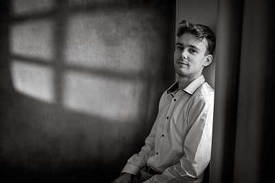 A black and white portrait of Pianist Thomas Summerfield sitting in window light.